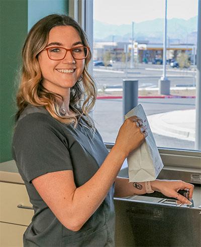 Photograph of a pharmacy employee at a drive-through window.